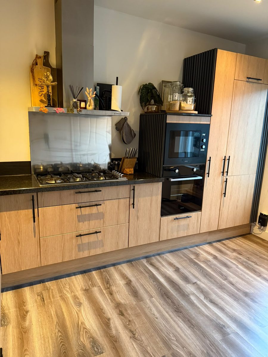 Keuken na renovatie: warme eiken houtlook gewrapt met zwart werkblad door WrapByDjam